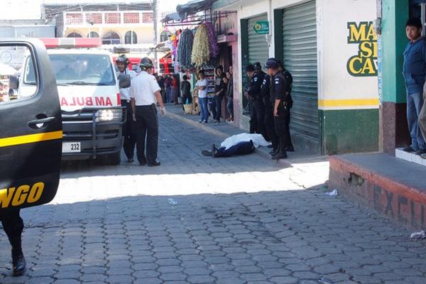 Policías y socorristas permanecen junto al cuerpo de un hombre muerto a balazos en la terminal de Chimaltenango. (Foto Prensa Libre: Víctor Chamalé)<br _mce_bogus="1"/>