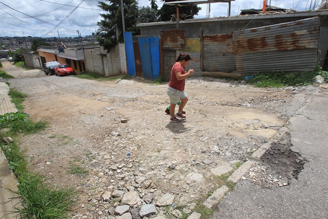 Vecina de Santa Genoveva 3, zona 18, camina en la calle deteriorada que fue mejorada con recursos de los residentes. (Foto Prensa Libre: Estuardo Paredes)