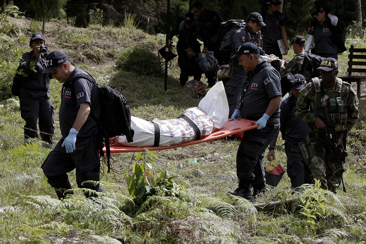 Forenses trasladan uno de los cadáveres hallados en la finca. (Foto Prensa Libre: EFE).