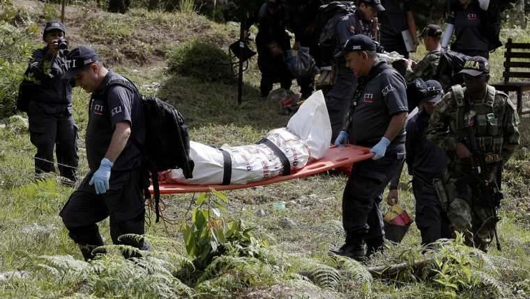 Forenses trasladan uno de los cadáveres hallados en la finca. (Foto Prensa Libre: EFE).