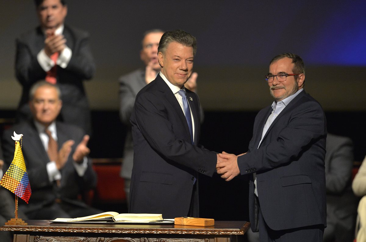 El presidente de Colombia, Juan Manuel Santos (izq.), saluda a Rodrigo Londoño, jefe máximo de las Farc, luego de la firma del nuevo acuerdo en Bogotá. (Foto Prensa Libre: AFP).