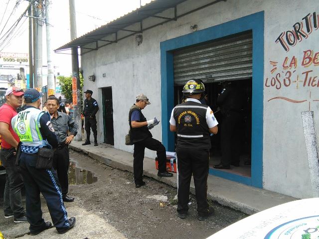 Policías inspeccionan la tortillería en la que fueron encontradas muertas dos mujeres, en Villa Nueva. (Foto Prensa Libre: Twitter)