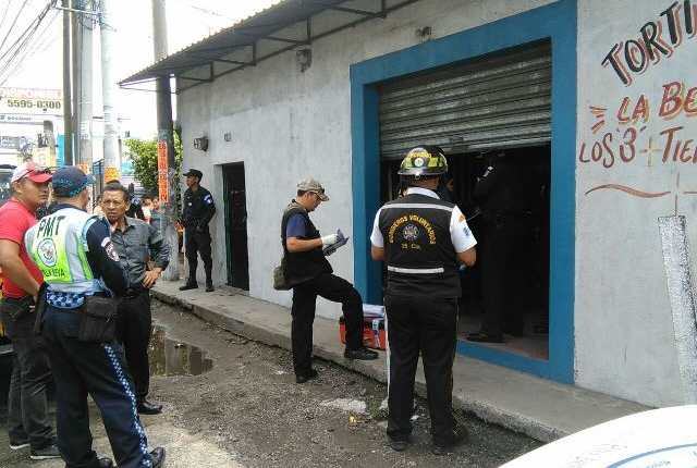 Policías inspeccionan la tortillería en la que fueron encontradas muertas dos mujeres, en Villa Nueva. (Foto Prensa Libre: Twitter)