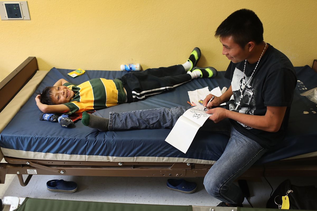 Un inmigrante guatemalteco identificado como Manuel junto a su hijo Agusto, 9 años en una casa facilitada para la reunificación en El Paso, Texas. (AFP)