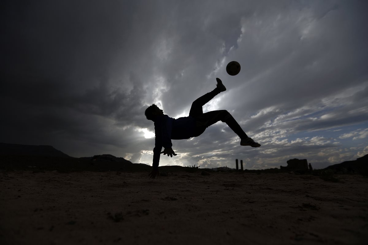 Un joven Yemeni patea el balón durante un juego de barrio con sus amigos en Sanaa. (Foto Prensa Libre: AFP)