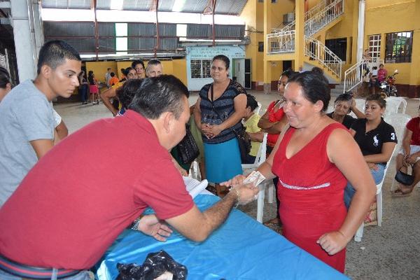 vecina recibe el bono de Q300  del alcalde Álex Sosa, en el salón de Río Hondo.
