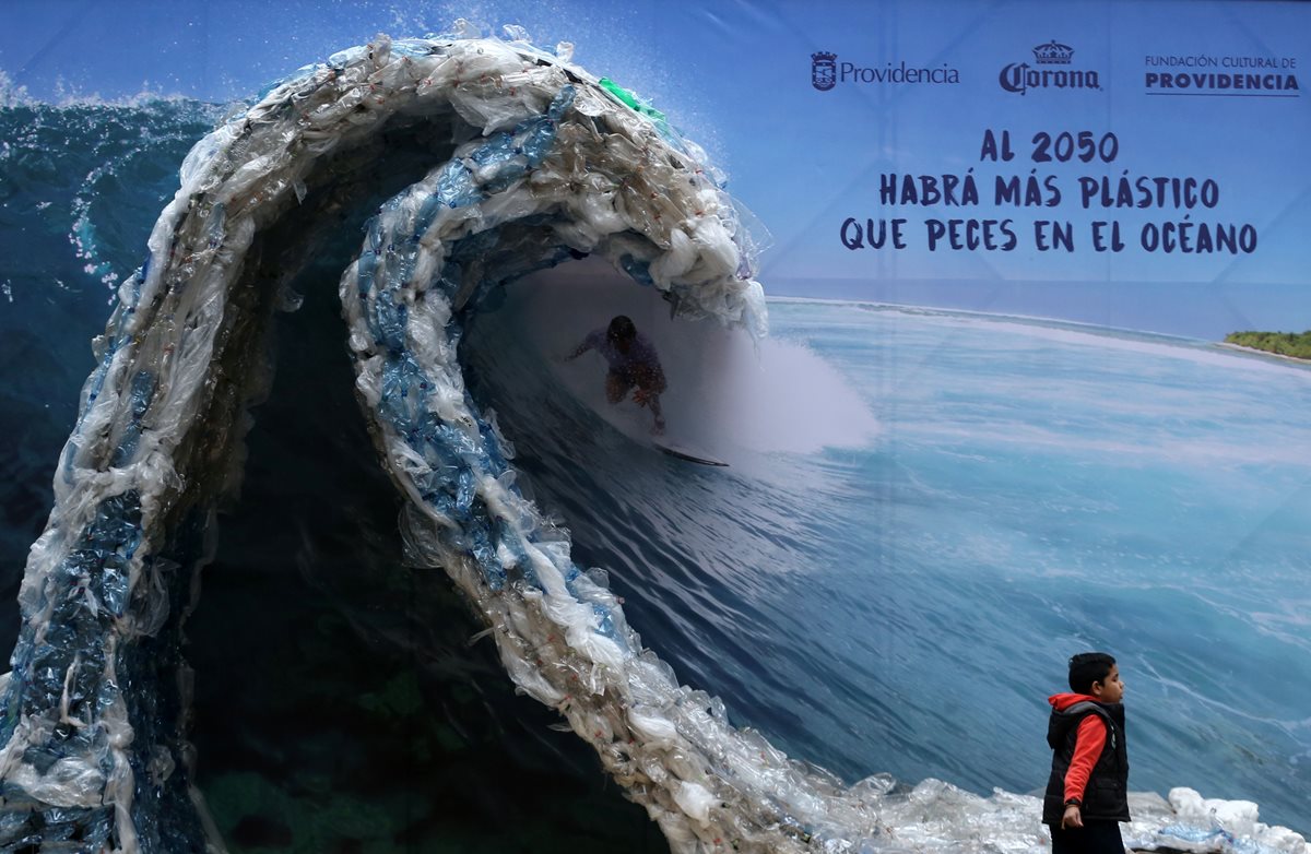 Una Manta publicitaria retrata a un hombre, surfeando una ola hecha de bolsas de plástico y botellas, para denunciar la contaminación de los océanos con motivo del Día Mundial del Medio Ambiente.(Foto prensa Libre:AFP)