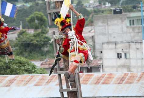 Danzantes, con trajes rojos, descienden ceremoniosamente, en representación de ángeles.