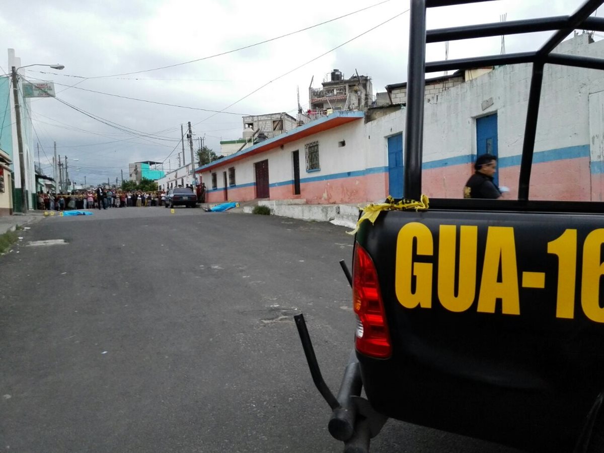 Bomberos Municipales de Mixco cubren uno de los cadáveres en la sección N de El Milagro. (Foto Prensa Libre: CBM)