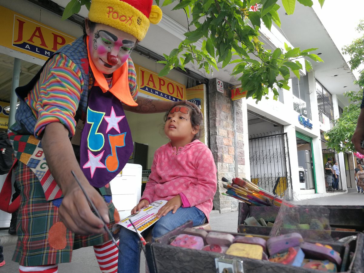 El payaso “Zancudito Show” maquilla el rostro de Brithany Cruz Morales, de 4 años, en el Paseo de la Sexta, zona 1 de la capital. (Foto Prensa Libre: César Pérez)