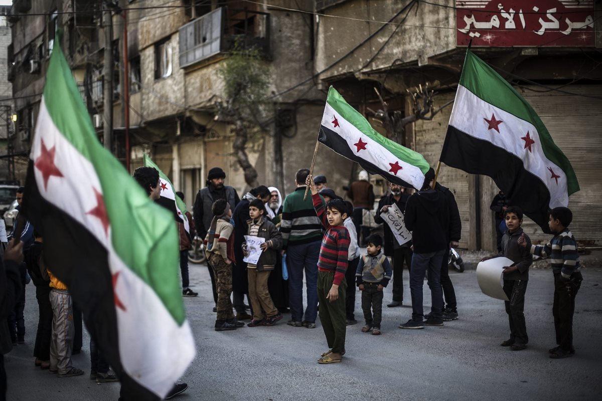 Un niño ondea la bandera de Siria, azotada por la guerra desde hace cinco años. (Foto Prensa Libre: EFE).
