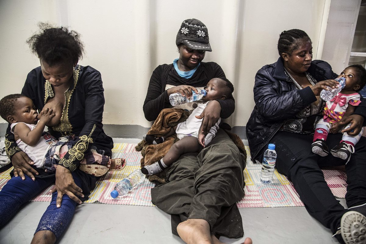 Tres mujeres nigerianas amamantan a sus bebés al desembarcar en Italia. Profundos cortes de arma blanca, heridas de bala y señales de violencia sexual son algunas de las marcas con las que los inmigrantes rescatados en el Mediterráneo desembarcan en ese país. (Foto Prensa Libre: EFE).