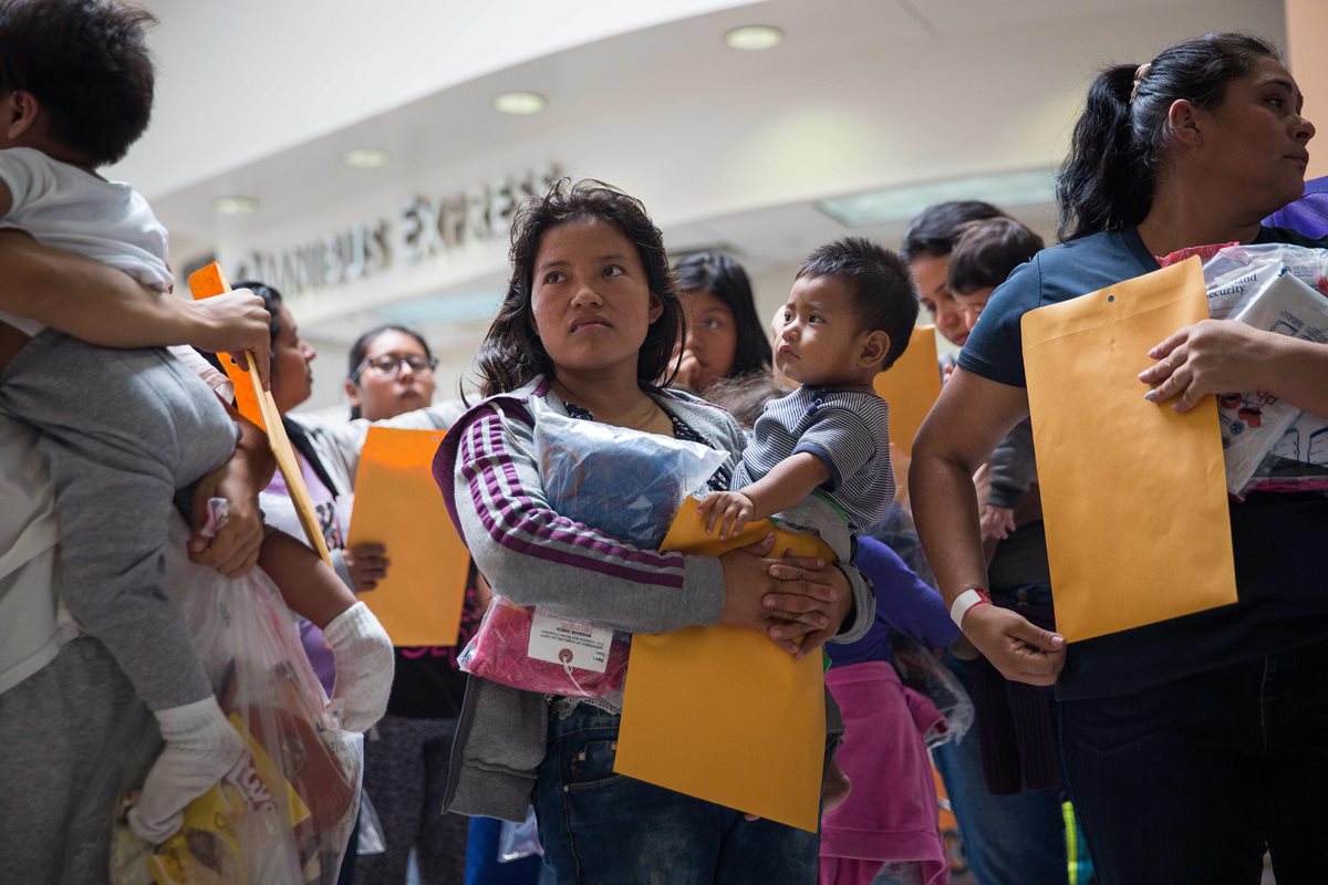 Madres junto a sus hijos migrantes esperan para dirigirse a un alberge cercano de Catholic Charities en Texas. (AFP).