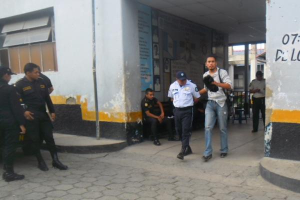 William Gustavo Cheguén Ajulón es conducido afuera de la comisaría por un miembro de la PNC. (Foto Prensa Libre: Edwin Paxtor)