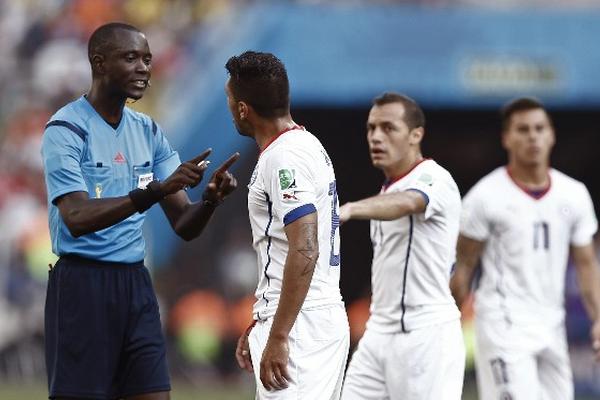El árbitro gambiano Bakary Gassama conversa con el defensa chileno Gonzalo Jara. (Foto Prensa Libre: EFE)