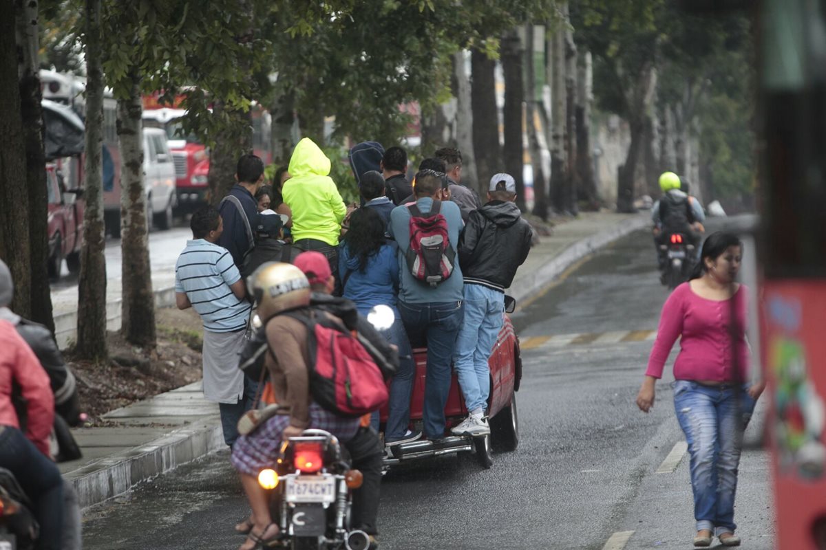 Ante la falta de buses urbanos, y la necesidad de salir a su trabajo, un usuario aceptó subir al baúl de un vehículo para continuar sus actividades (Foto Prensa Libre: Erick Avila). 