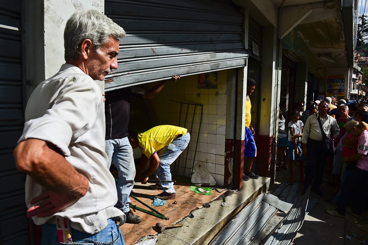 Un carnicero intenta recuperar algo de su negocio luego de los saqueos ocurridos en la favela de Petare, Venezuela, la madrugada del viernes. (Foto Prensa Libre: AFP).