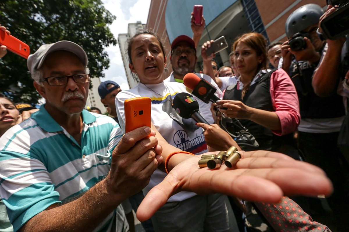 La diputada Gaby Arellano muestra a la prensa cartuchos de bala disparados por civiles encapuchados contra marcha. (Foto Prensa Libre: EFE)