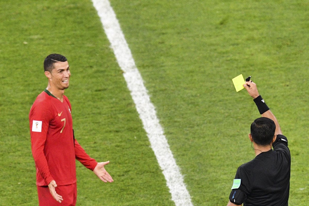 El árbitro Enrique Cáceres muestra la tarjeta amarilla a Cristiano luego de revisar el VAR. (Foto Prensa Libre: AFP)