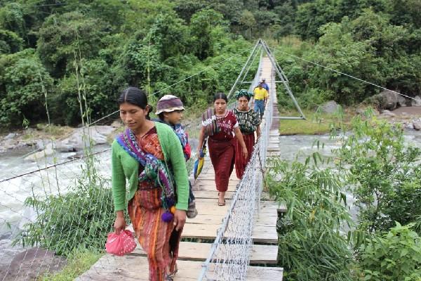 Vecinos de  Unión Victoria cruzan por un puente de hamaca sobre el río Madre Vieja.