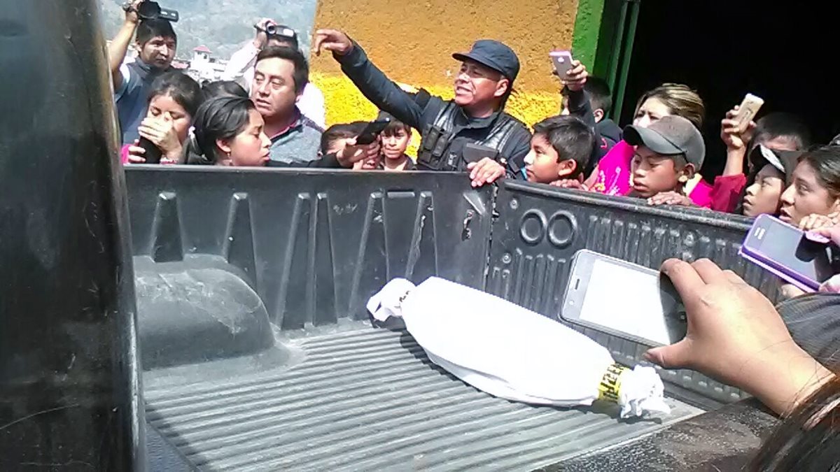 Curiosos permanecen junto a patrulla de la PNC que traslada feto localizado en Nebaj. (Foto Prensa Libre: Óscar Figueroa).