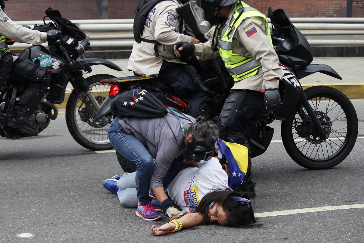 Las personas de las motocicletas se bajan para agredir a los manifestantes.
