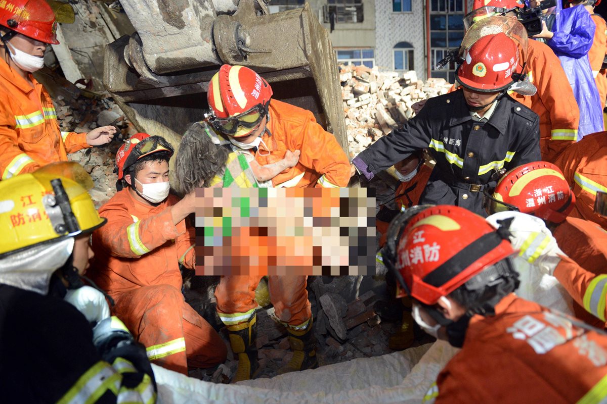 El momento en el que la pequeña Wu Ningxi es rescatada al sobrevivir en los brazos de sus padres muertos. (Foto Prensa Libre: AFP).