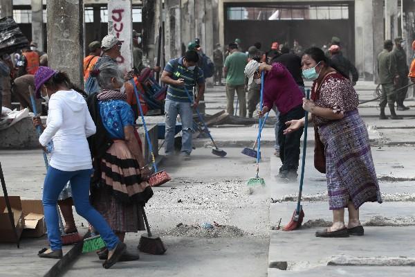 Vendedores de La Terminal limpian las áreas dañadas por el reciente incendio en el mercado.