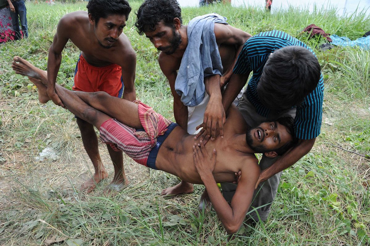 Unos hombres tratan de ayudar a un compañero enfermo que desembarcó en las costas tailandesas. (Foto Prensa Libre: AFP).