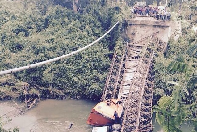 Vecinos de la comunidad Cruce El Rosario observan un tráiler que cayó al vacío cuando colapsó el puente que une a comunidades de Dolores y Melchor de Mencos, Petén. (Foto Prensa Libre: Rigoberto Escobar)