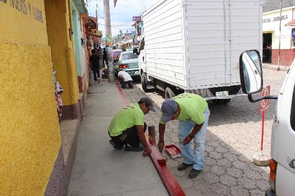 Empleados ediles pintan bordillo.