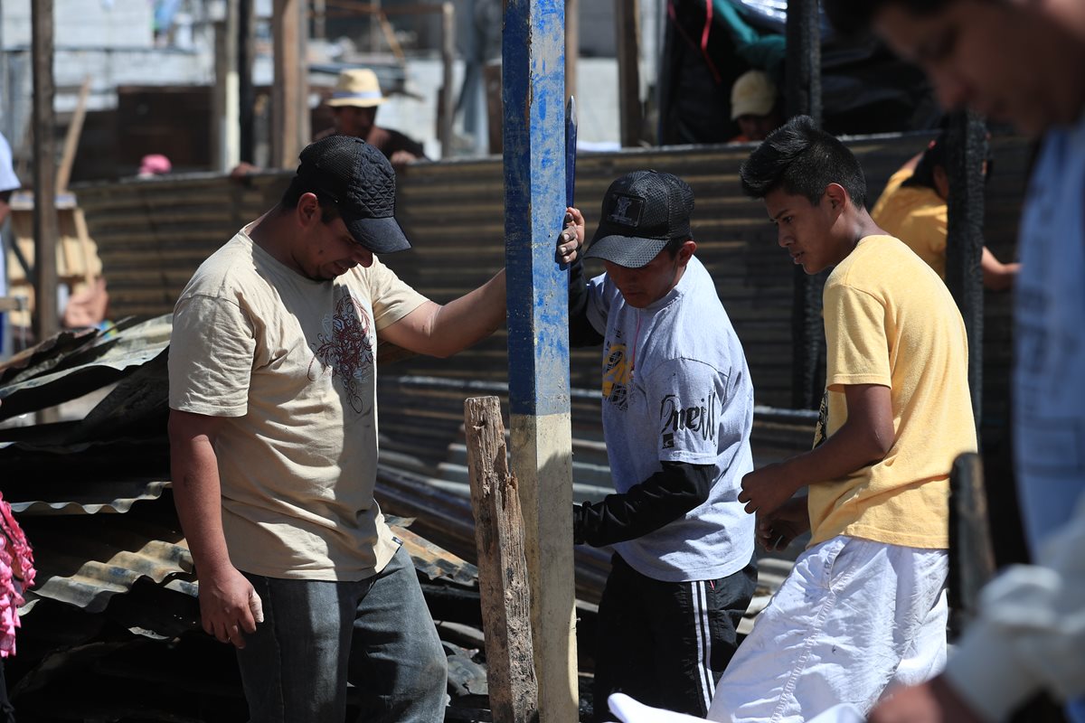 Un grupo de hombre excava para colocar parales de madera y reconstruir viviendas que fueron destruidas por el incendio. (Foto Prensa Libre: Carlos Hernández)
