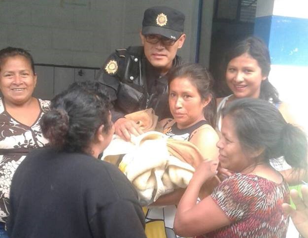 El agente de la PNC junto a un grupo de personas observa a la bebé. (Foto Prensa Libre: PNC).