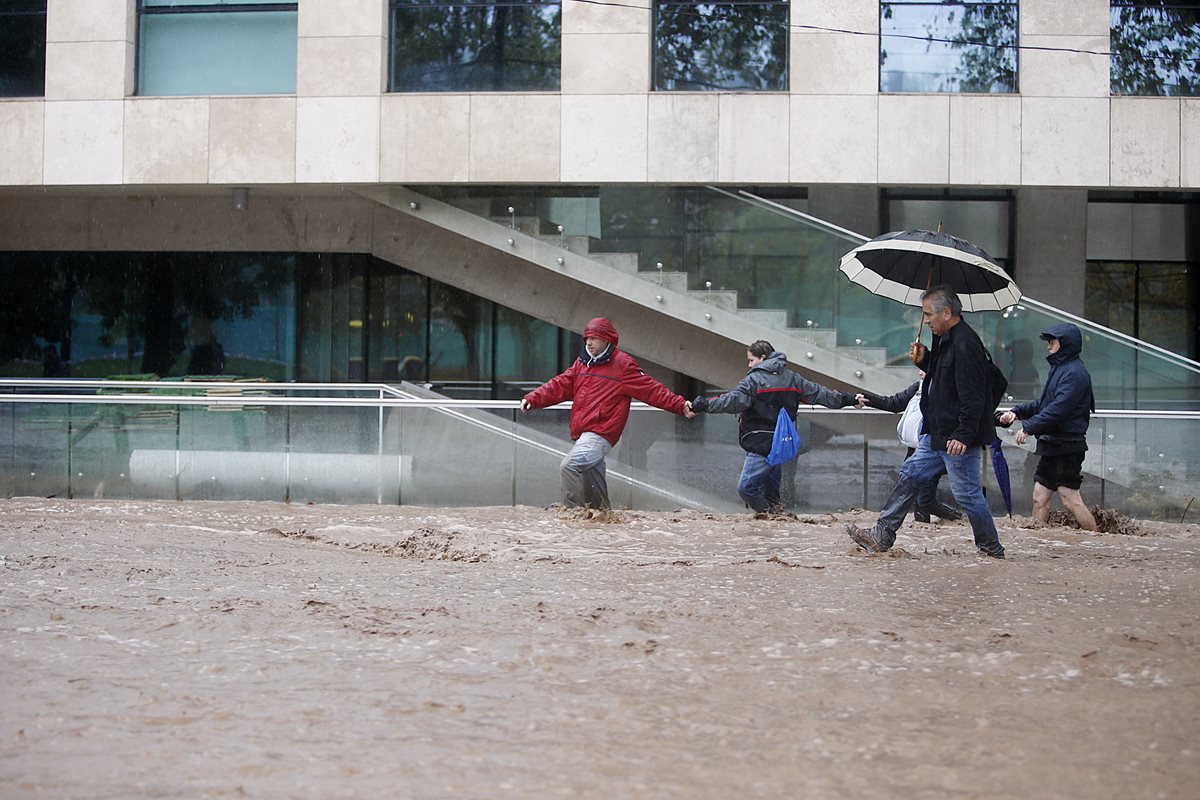 Un grupo de personas camina por una inundada calle de Santiago, capital de Chile. (Foto Prensa Libre: EFE).