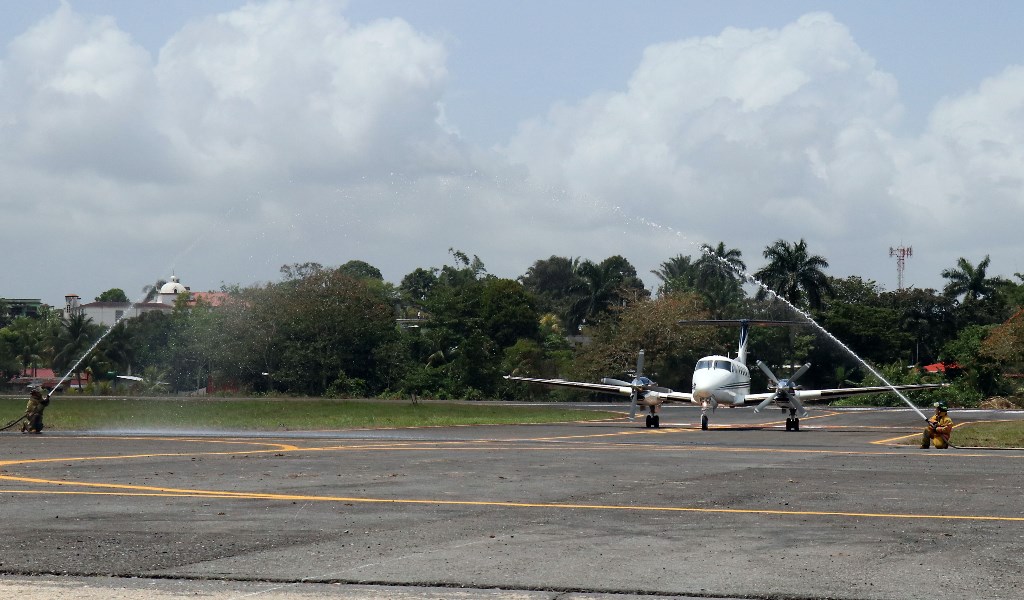 Bomberos Voluntarios lanzan agua al primer vuelo oficial que aterriza en el aeropuerto La Tierra de Dios, de Puerto Barrios, Izabal. (Foto Prensa Libre: Dony Stewart)