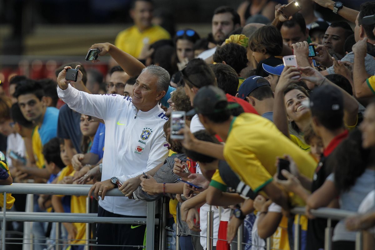 El entrenador de Brasil, Tite se toma una selfie con los aficionados que llegaron al entrenamiento. (Foto Prensa Libre: EFE)