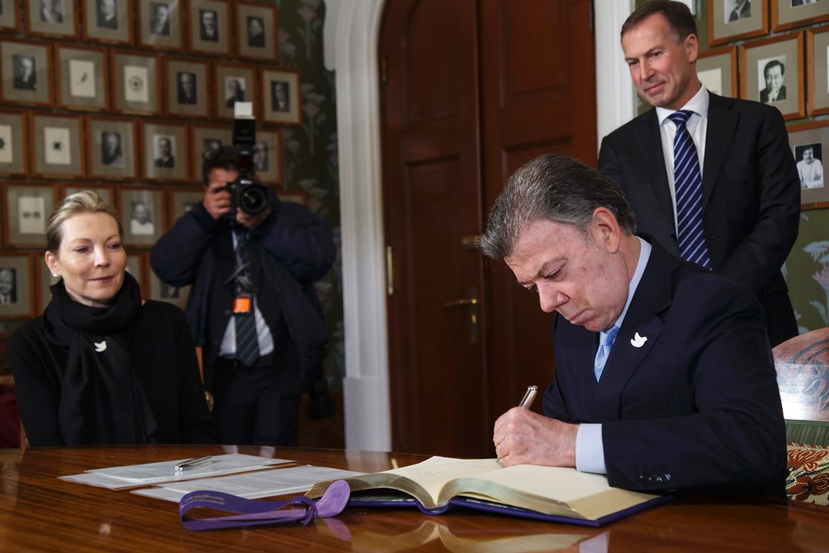 Juan Manuel Santos firma el libro de protocolo del Instituto Nobel en Noruega, en presencia de su esposa, María Clemencia. (Foto Prensa Libre: AFP)