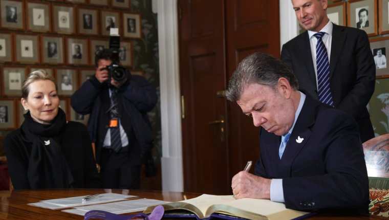Juan Manuel Santos firma el libro de protocolo del Instituto Nobel en Noruega, en presencia de su esposa, María Clemencia. (Foto Prensa Libre: AFP).