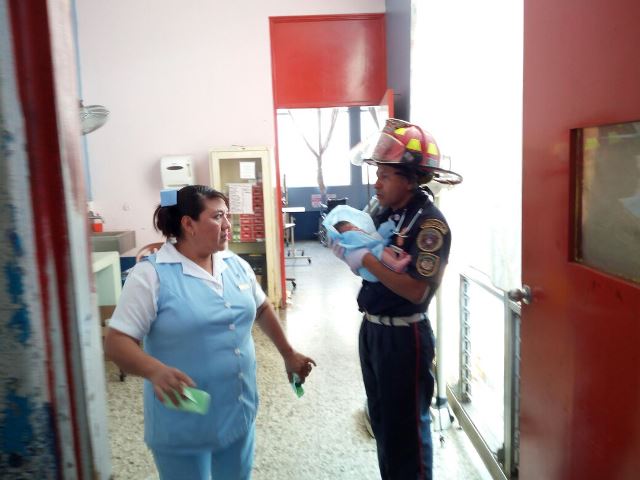 El bombero Wilfredo Morales entrega a una enfermera la bebé rescatada en San Andrés Villa Seca, Retalhuleu. (Foto Prensa Libre: Rolando Miranda)