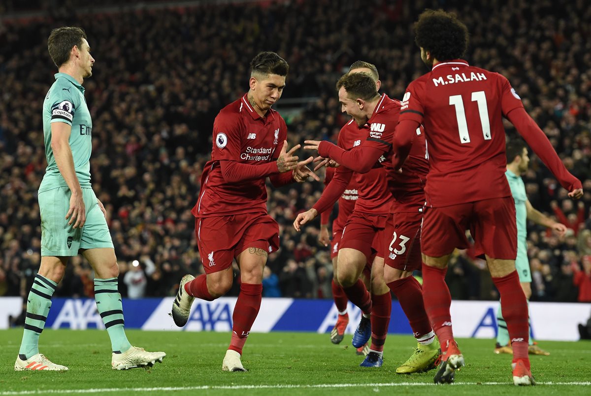 Roberto Firmino (centro), festeja con sus compañeros después de haber marcado un gol para el Liverpool en el juego contra el Arsenal. (Foto Prensa Libre: AFP).