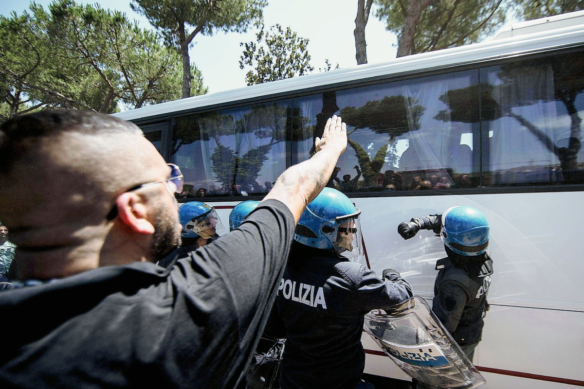 Un manifestante frente a autobús de refugiados mientras la policía intenta dispersar la protesta en Roma. (Foto Prensa LIbre:AFP)