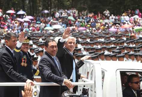 El presidente  Otto Pérez, junto al ministro Mauricio López, saludan a la concurrencia desde un vehículo.