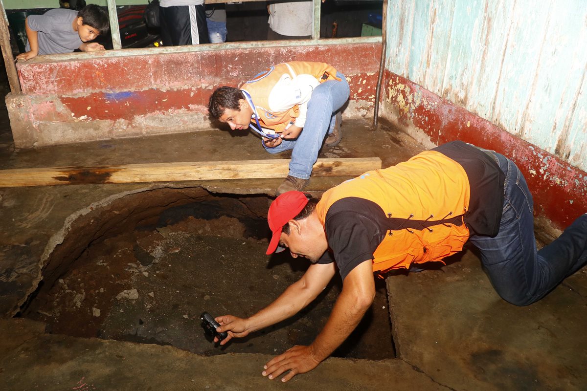 Personal de la Conred evalúa el diámetro del agujero que se formó en una vivienda del barrio Monterrey, zona 4 de Retalhuleu. (Foto Prensa Libre: Rolando Miranda)