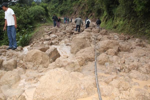 Las personas que viajaban en esa ruta se vieron obligadas a caminar y transbordar a causa del derrumbe en el cerro Lec. (Foto Prensa Libre: Ángel Julajuj)<br _mce_bogus="1"/>