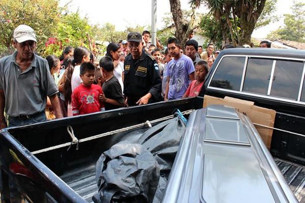 Un agente de la PNC y curiosos observan el féretro de José Isaías Segura Agustín, asesinado en San Pedro Pinula. (Foto Prensa Libre: Hugo Oliva)
