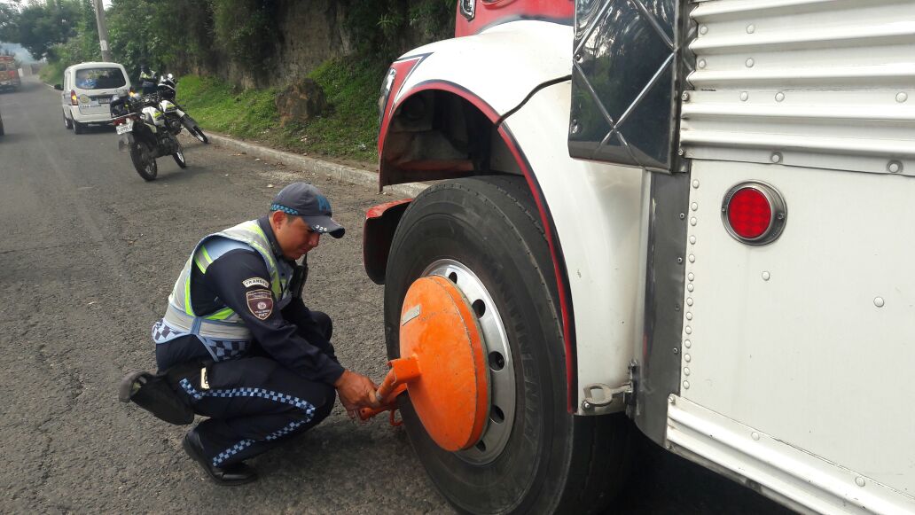 Un agente de la PMT de Villa Nueva inmoviliza un autobús por tener multas pendientes desde el año pasado. (Foto Prensa Libre: Dalia Santos)