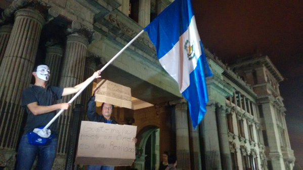 Uno de los manifestantes con el rostro cubierto, ondea un Pabellón Nacional frente al Palacio Nacional de la Cultura. (Foto Prensa Libre: @drmarcolomo)