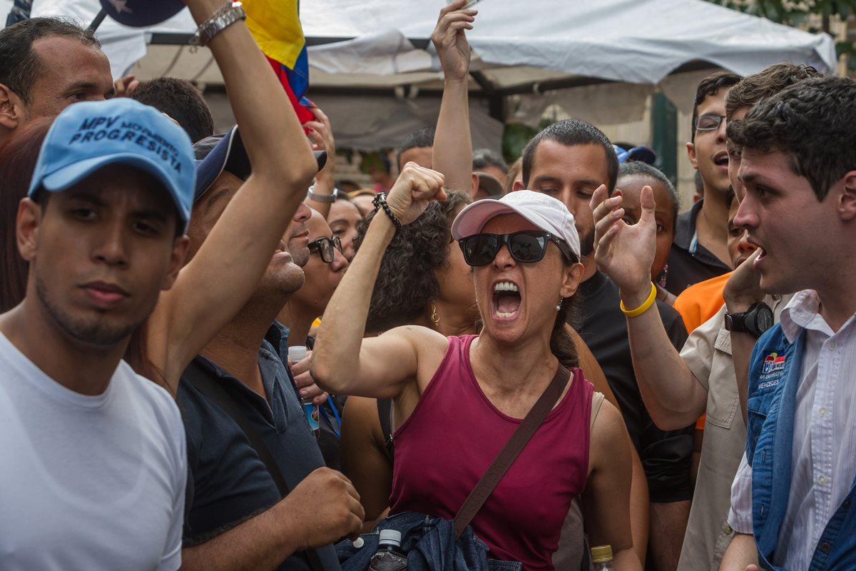 Venezolanos opositores al gobierno de Maduro gritan consignas en las afueras del Consejo Nacional Electoral. (Foto Prensa Libre: EFE).
