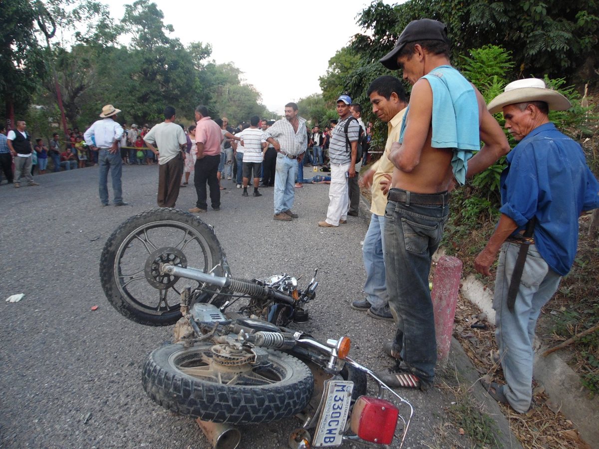 Testigos observan la motocicleta en la que se movilizaban los hermanos Gutiérrez. (Foto Prensa Libre: Víctor Gómez)