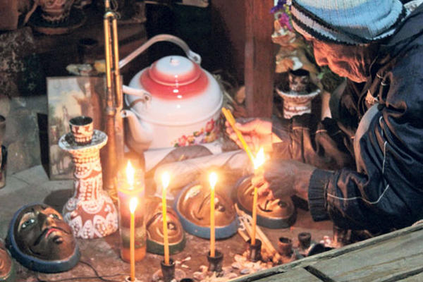 El rezador Santiago Díaz coloca una ofrenda ante las máscaras.